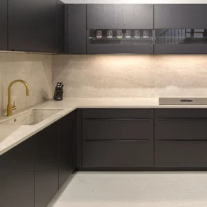 Cocina moderna con muebles oscuros y encimera clara.