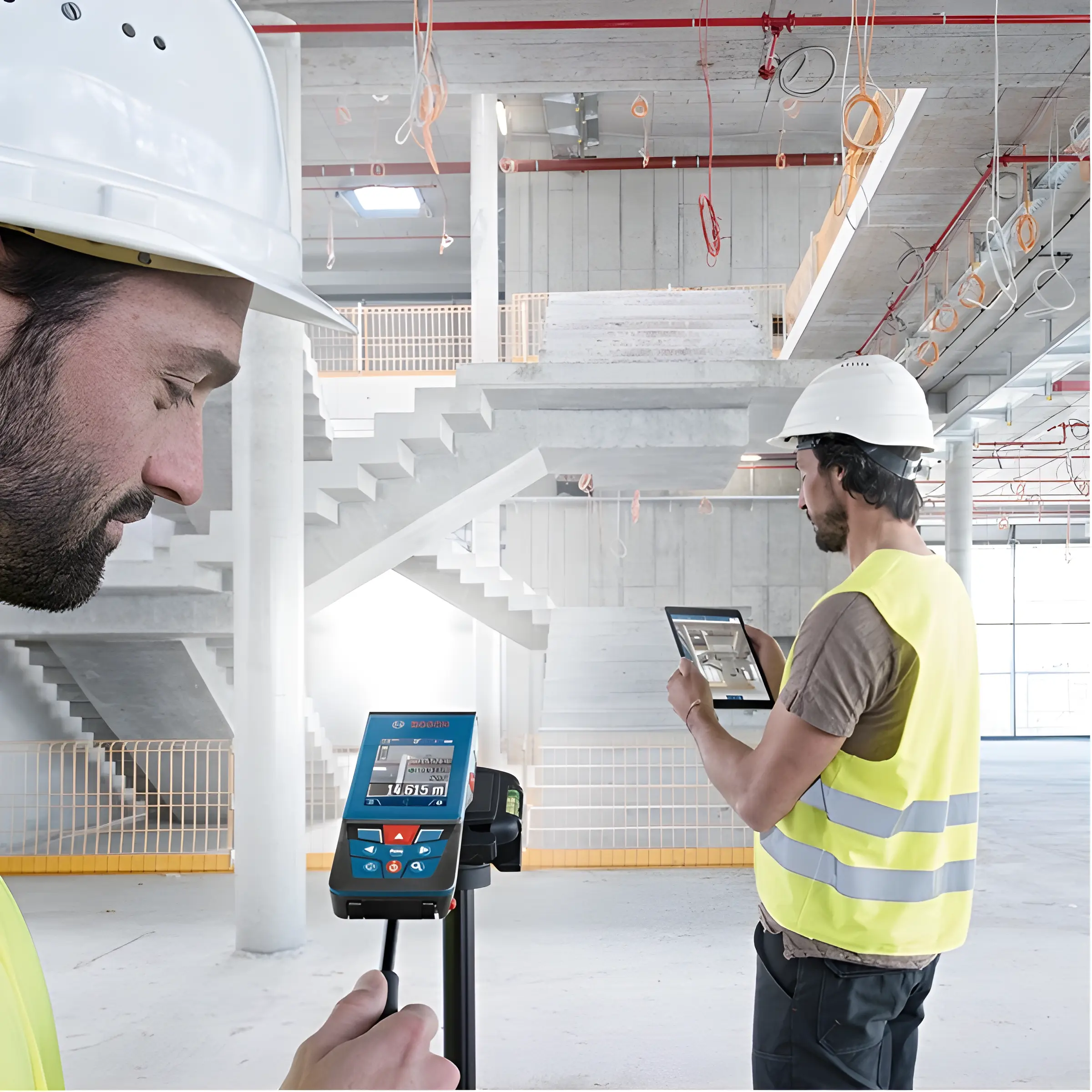 Trabajadores con casco en obra verificando planos digitales.