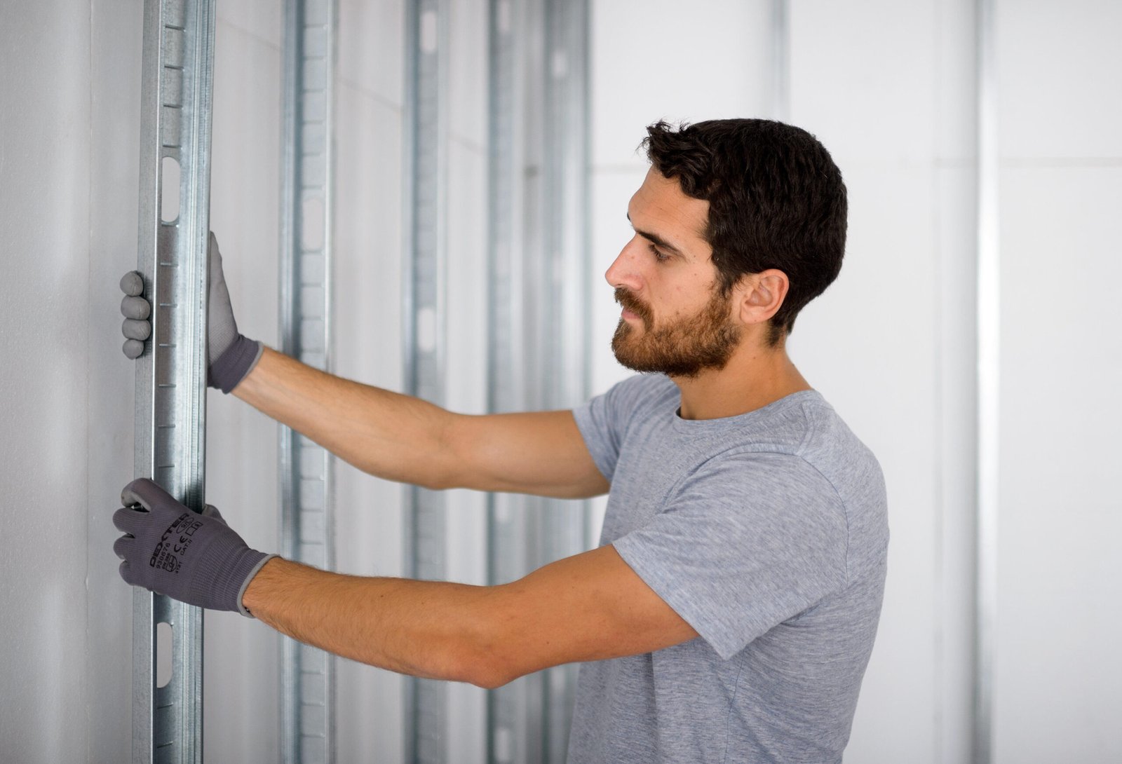 Hombre instalando estructura metálica en pared.